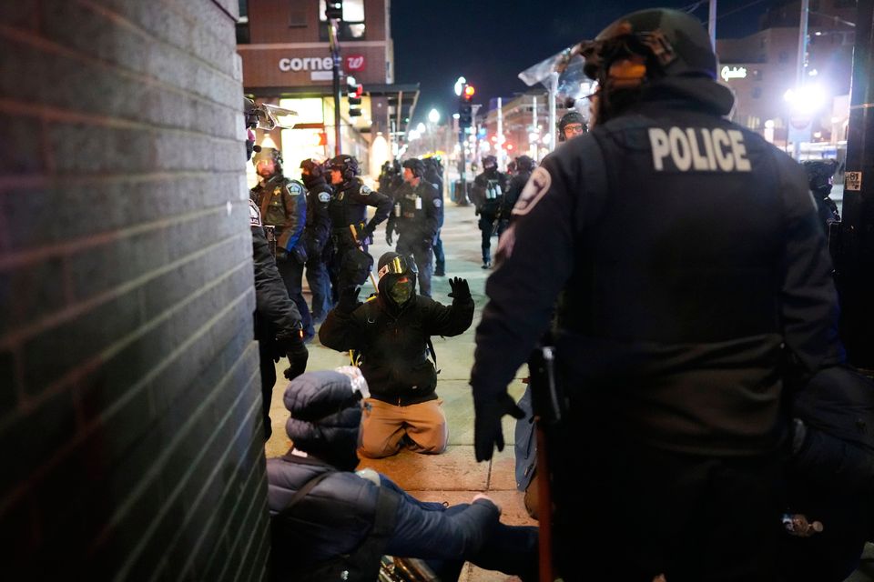 A protester raises their arms on the ground as law enforcement make arrests after declaring an unlawful assembly during a noise demonstration outside the Graduate by Hilton Minneapolis hotel on Wednesday, Jan. 28, 2026, in Minneapolis. (AP Photo/Adam Gray)