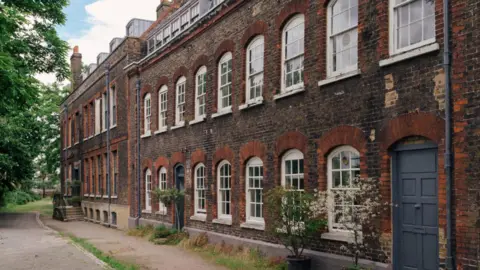 Master Shipwrights House Exterior of brick building shows nine white sash windows upstairs and another seven downstairs plus a grey front door