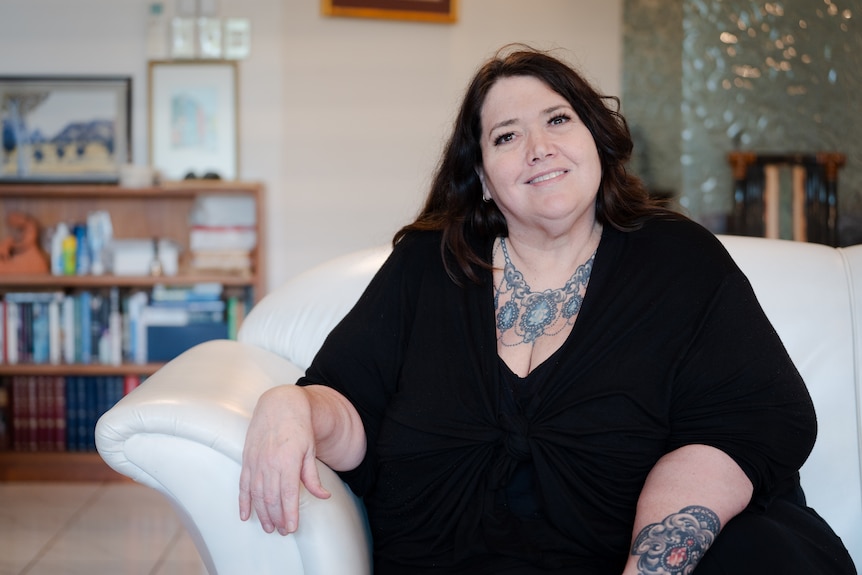 A woman wearing a dark shirt smiles at the camera.