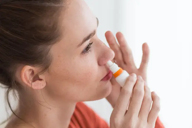 Woman using nasal spray for controlling rhinitis.