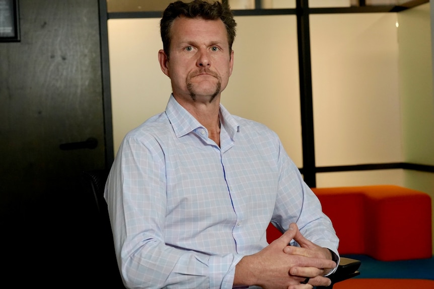 Man with stern face holds hands together