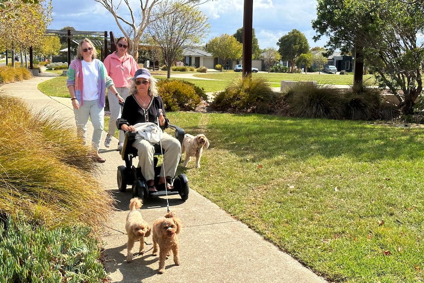 Karen sits on a motorised buggy as her daughters walk behind her.