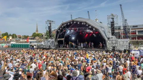 Paul Box A large crowd watching a band performing on the Harbour Festival's main stage during the day