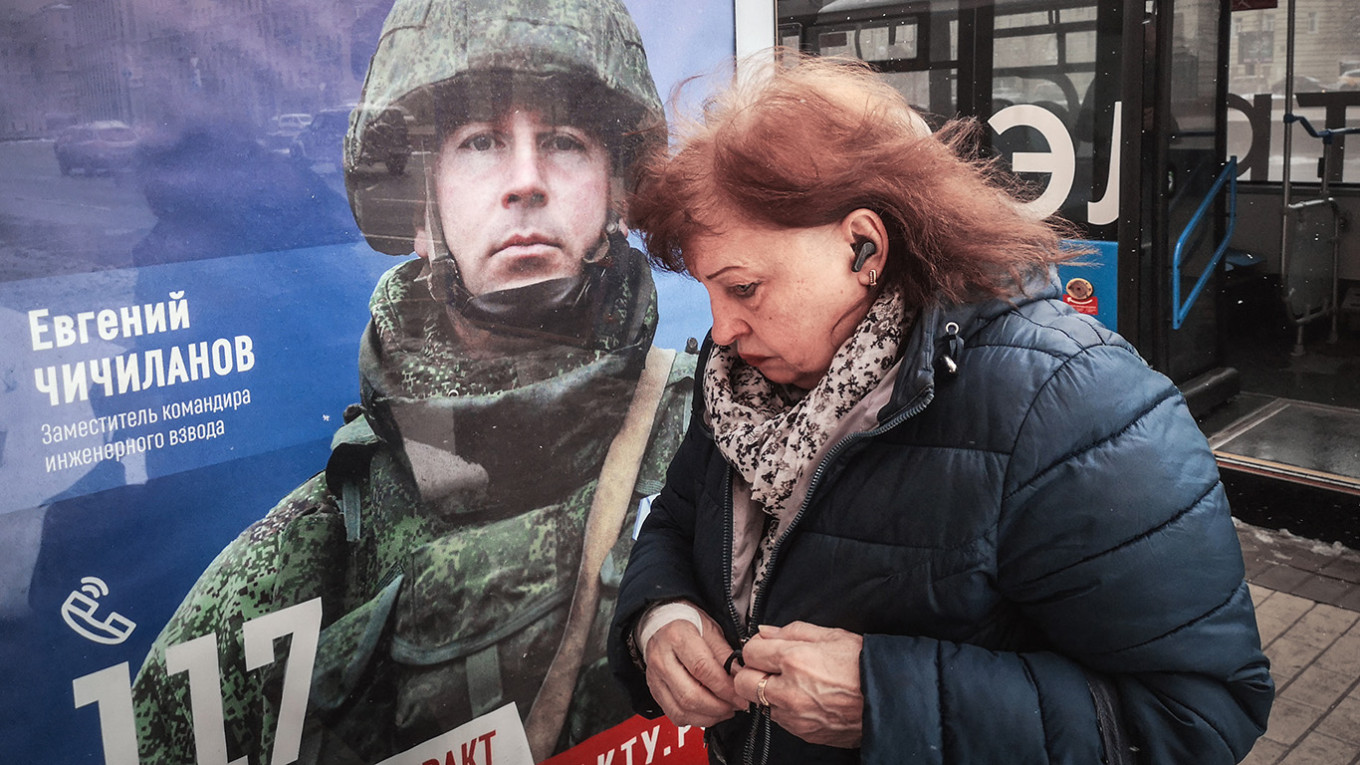 A woman walks past a poster promoting contract army service in Moscow. Alexander Nemenov / AFP