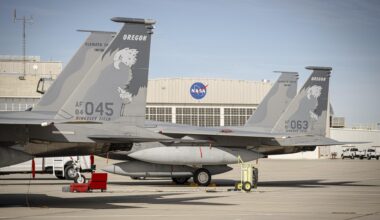 Two F-15 aircraft sit side by side on the ramp at NASA’s Armstrong Flight Research Center, displaying tail numbers 045 and 063 and tail markings that read “Oregon” above an eagle graphic. A NASA hangar with the agency’s logo is visible in the background