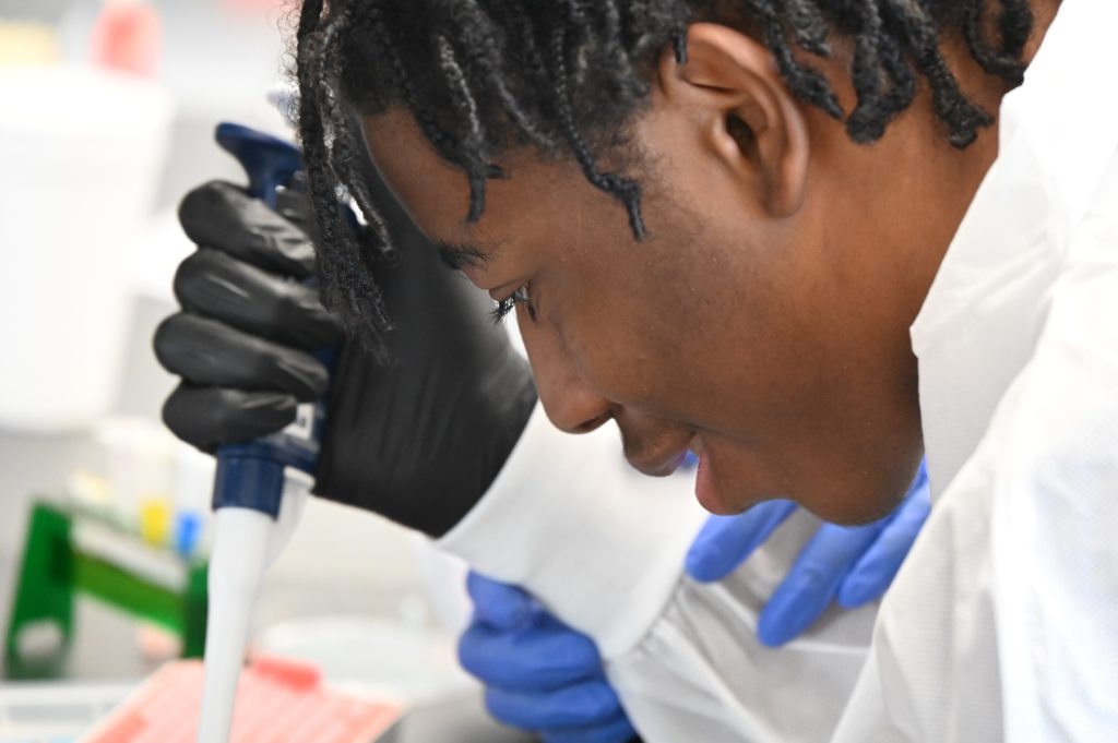 High school students learn about cancer research and how to use lab equipment in a modern laboratory.
