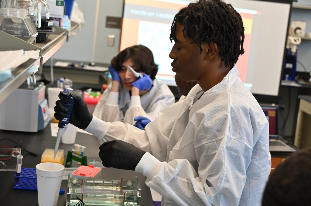 High school students learn about cancer research and how to use lab equipment in a modern laboratory.