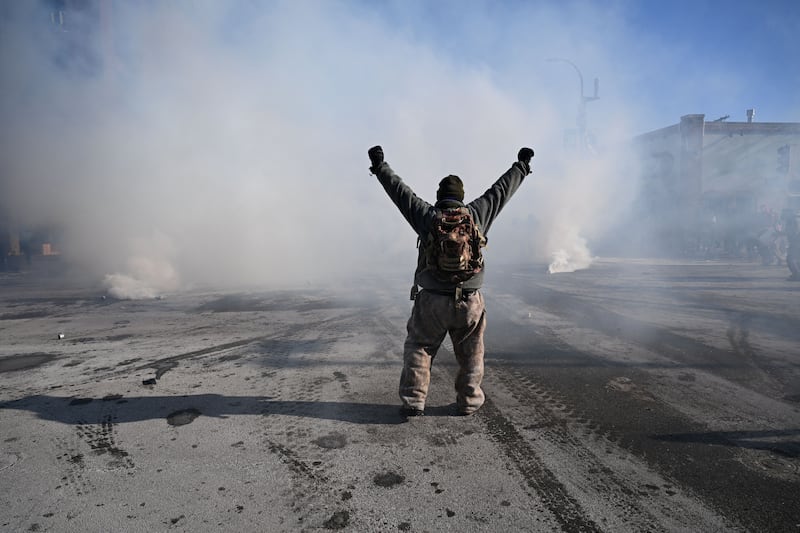 A protester faces a barrage of gas projectiles fired by Minneapolis police officers near where a man was shot dead by federal immigration agents in Minneapolis, Minnesota, on January 24, 2026. (Photo by Roberto Schmidt / AFP via Getty Images)