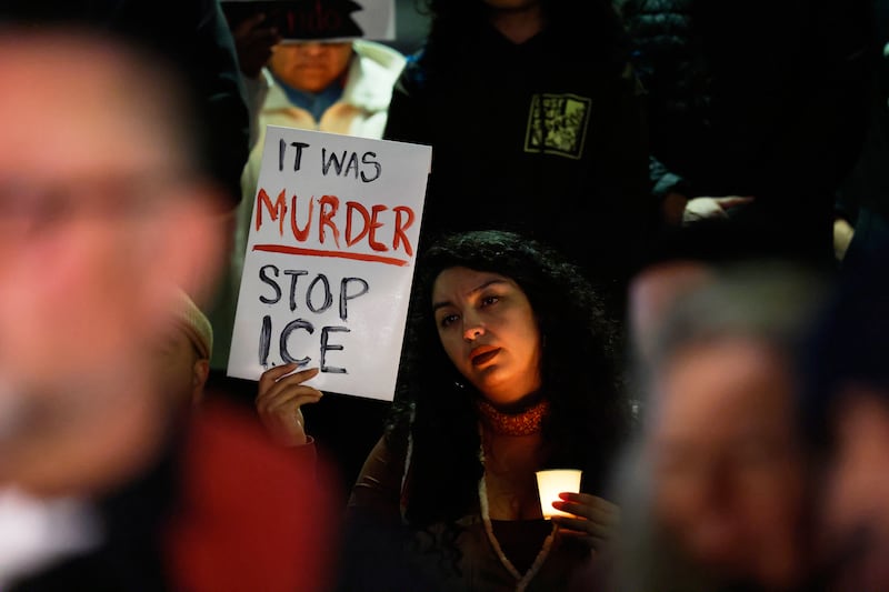 A demonstrator holds a sign during a candlelight vigil during a protest in response to the fatal shooting of 37-year-old Alex Pretti in Minneapolis (Photo by Caroline Brehman/AP)