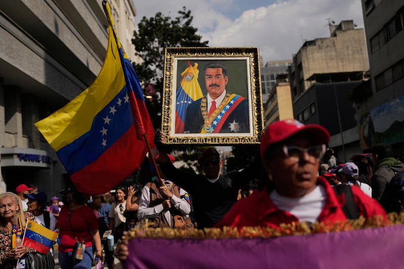 A government supporter holds an image of Nicolas Maduro during a women’s march to demand his return in Caracas, Venezuela on Tuesday. Photograph: Matias Delacroix/AP