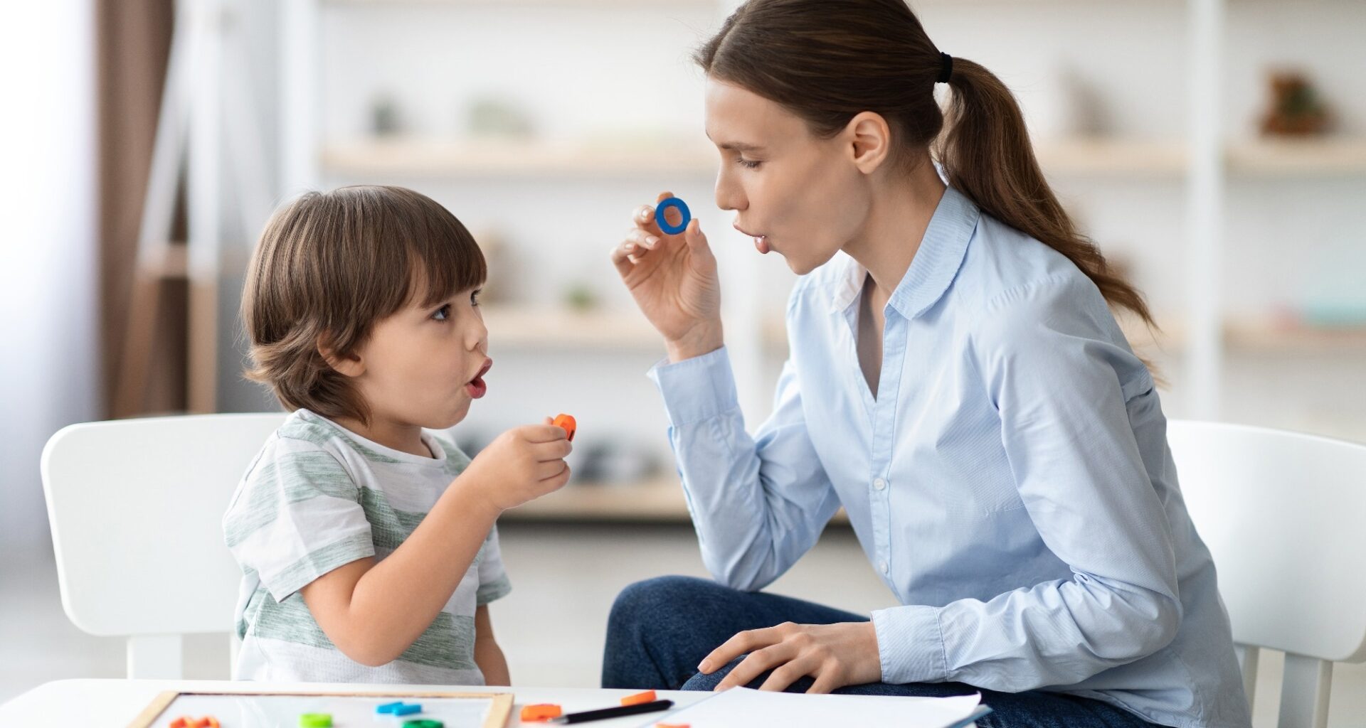 Little boy learning letter O with private English language tutor during lesson at office