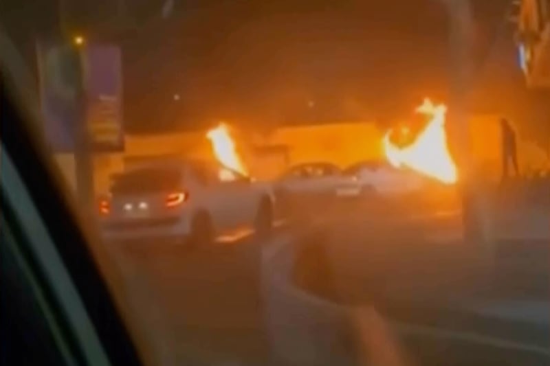 Iranian state television images showing cars driving past burning vehicles in Tehran. Photograph: Iranian state TV via AP