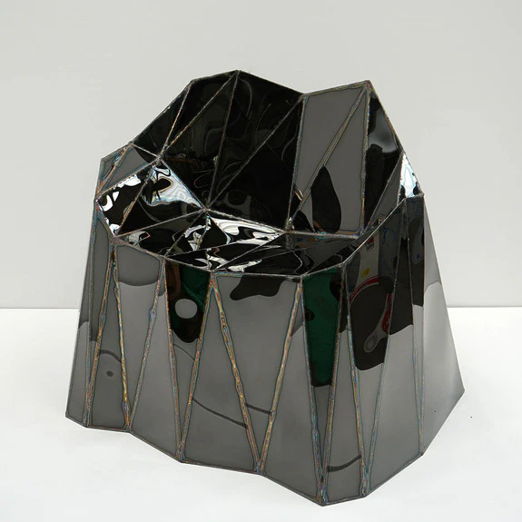 Geometric black chair with an angular, modern design on a white background.