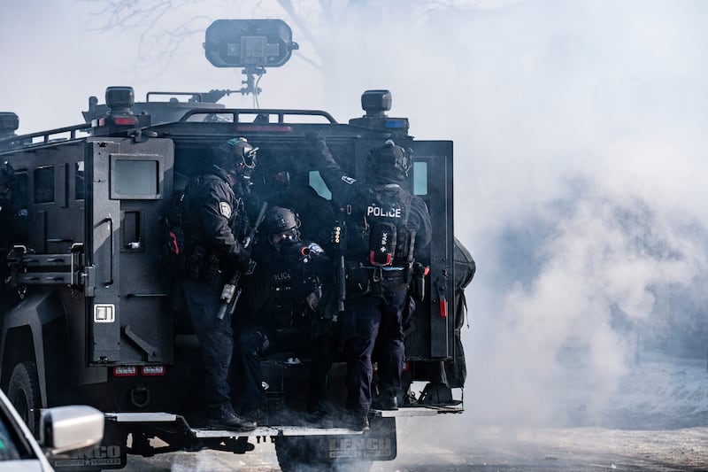 Minneapolis police officers ride an armoured vehicle after releasing gas canisters at protesters near where a man was shot dead by federal immigration agents in Minneapolis, Minnesota, on January 24, 2026. (Photo by Roberto Schmidt / AFP via Getty Images)