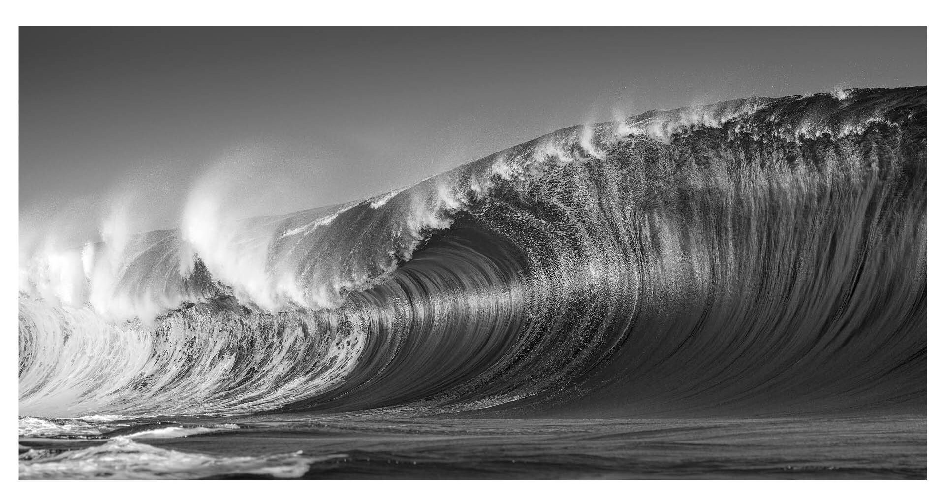 Photograph titled 'Exploding Swell' by Ted Grambeau of Australia, winner of the General (black and white) category in the 14th season of the HIPA (Hamdan bin Mohammed bin Rashid Al Maktoum International Photography Award) photography competition. Image description: On a Pacific reef, a massive swell surges, its waves crashing with unrelenting force. Spray erupts upward, curling in wild arcs before collapsing into the churning sea. The ocean's raw power is vividly displayed through this magnificent wave, a dream for surfers and a captivating subject for photographers.