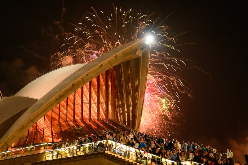 SYDNEY, AUSTRALIA - DECEMBER 31: People enjoy the New Year's Eve firework displays at Opera House on December 31, 2025 in Sydney, Australia. Thousands turned out to celebrate New Year's Eve in Sydney, as the Harbour Bridge lit up with fireworks. (Photo by George Chan/Getty Images)