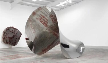 Abstract metallic and textured sculptures in a modern art gallery setting with high ceilings and bright lighting.