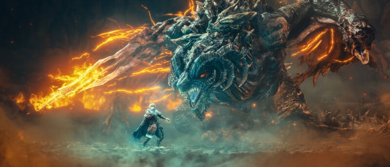 A lone warrior in a flowing cape faces a massive, menacing dragon with glowing orange eyes and fiery cracks on its body, as flames erupt from its arm in a dramatic, smoky battlefield.