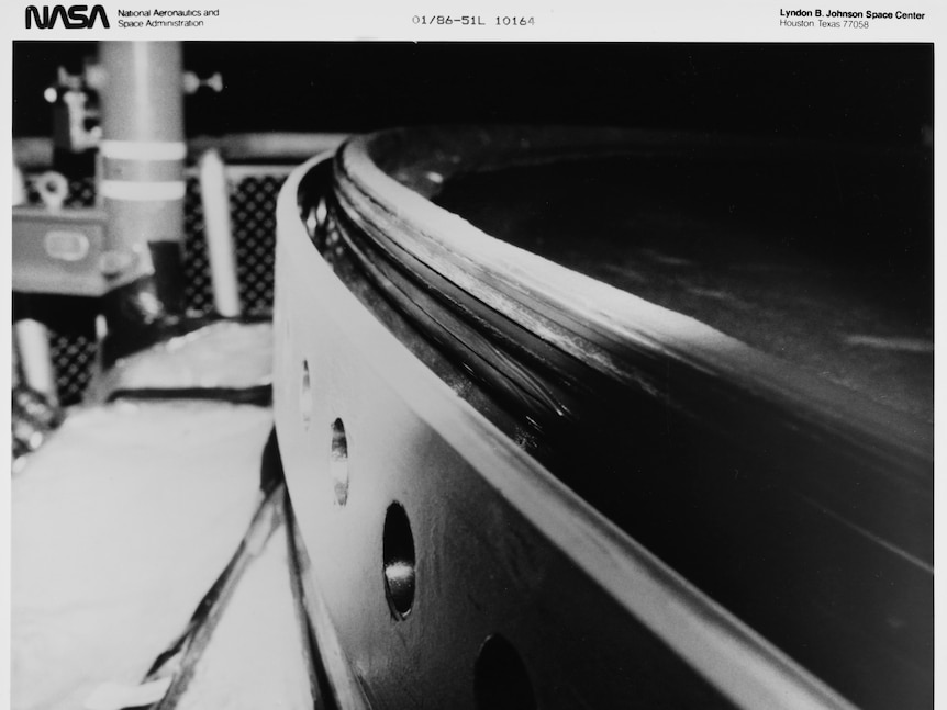 Black-and-white close-up photo of a rubber O-ring sitting within a groove, just inside the edge of a large metal cylinder.