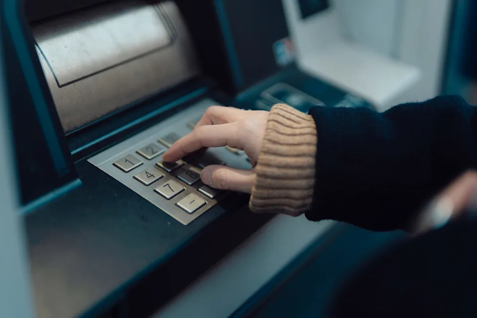 Cropped shot of a woman's hand withdrawing cash, depositing money, paying financial bills, transferring fund, checking account balance at the automatic cash machine (ATM). Auto financial service. Personal banking.