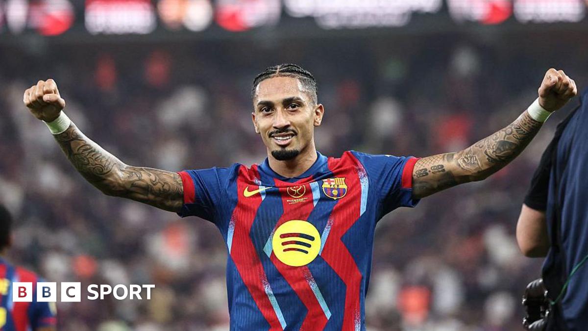 Raphinha, wearing a Barcelona shirt, spreads his arms wide in celebration