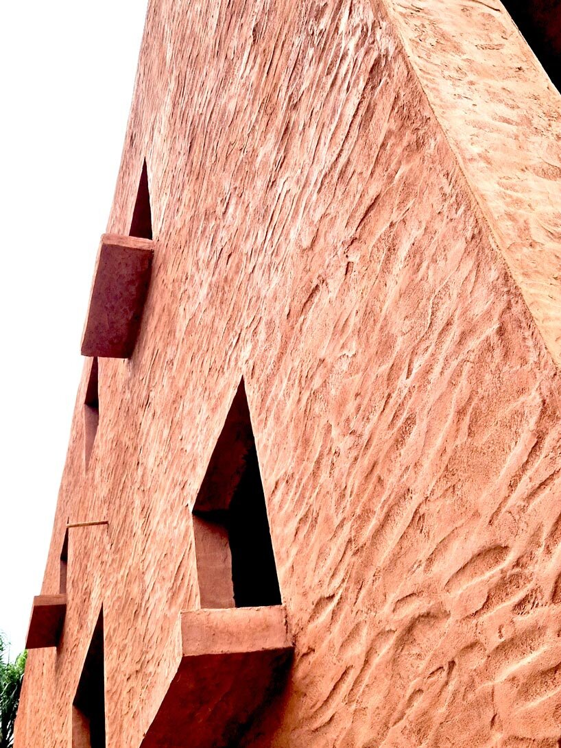 clay-pigmented monolithic villas emerge from ghana’s red earth landscape