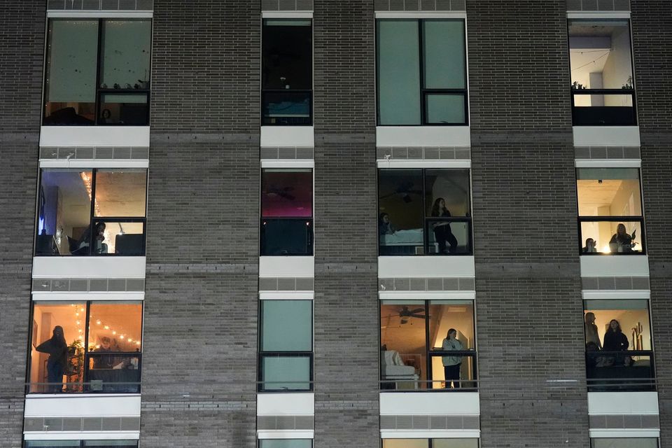 People watch from a building as police prepare to make arrests during a noise demonstration outside the Graduate by Hilton Minneapolis hotel on Wednesday, Jan. 28, 2026, in Minneapolis. (AP Photo/Adam Gray)