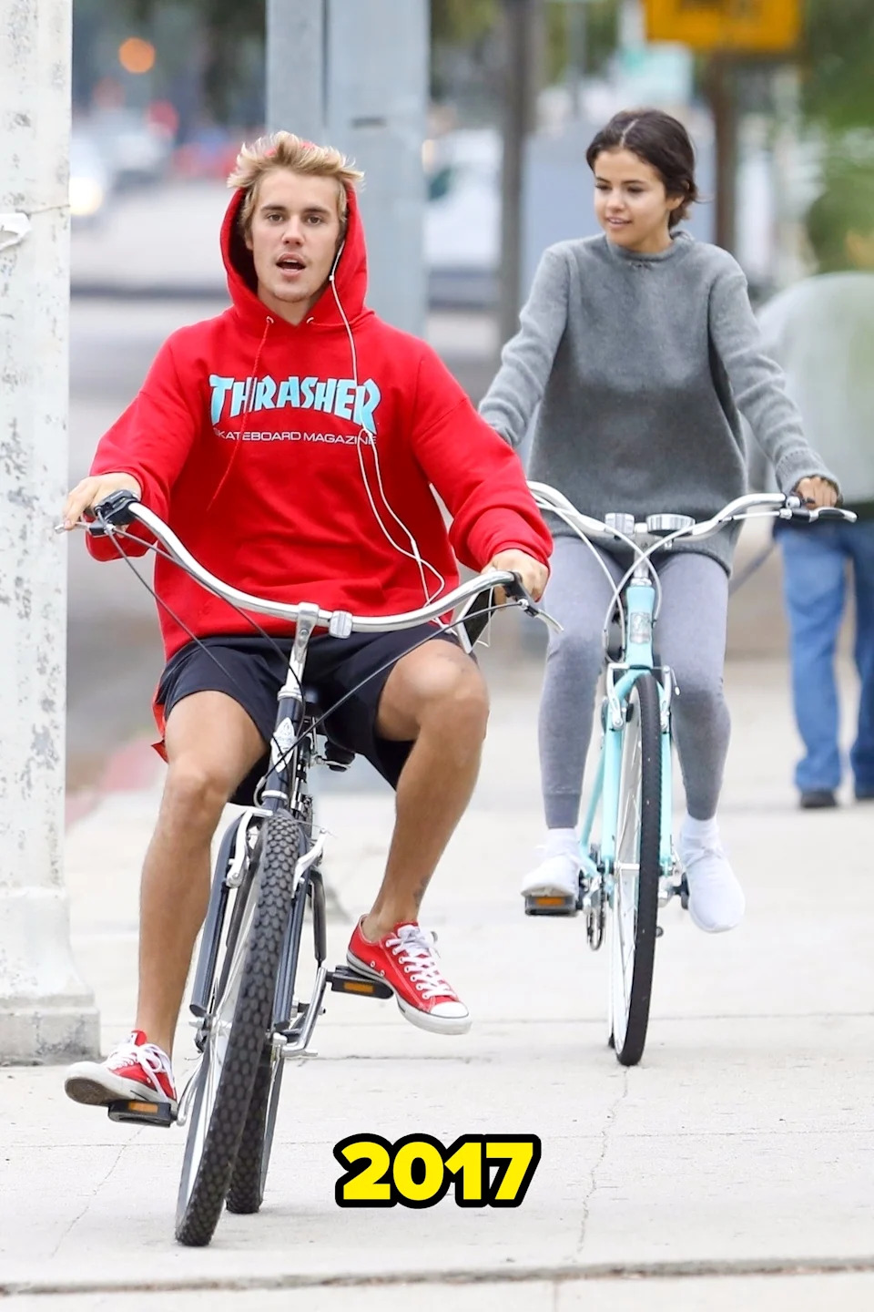 Justin and Selena casually riding bikes on a sidewalk