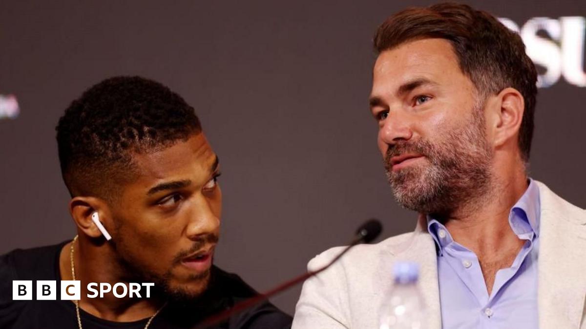 Anthony Joshua sits between Sina Ghami and Latif Ayodele as all wear training kit, with a grassy area behind the three men
