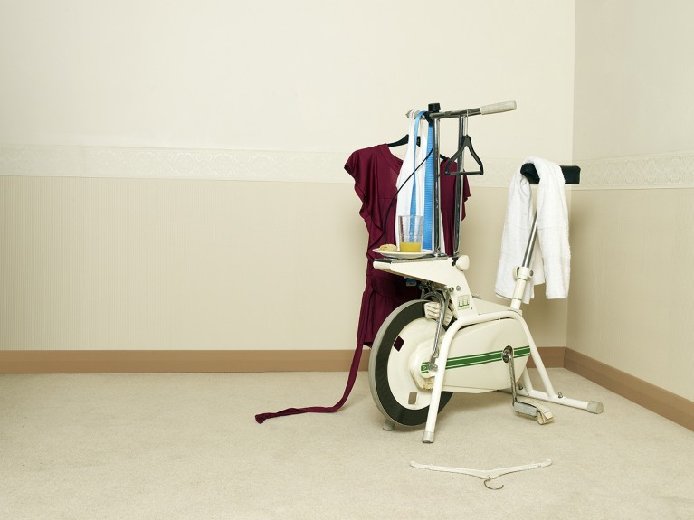 An exercise bike with clothes hanging on it.