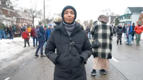 Eloise Alanna/BBC A woman stands next to the site of Renee Good shooting