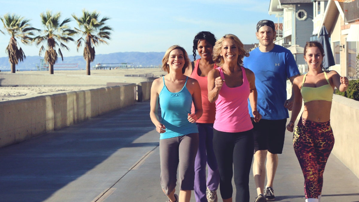 Denise Austin leading a group of people on a walk near the beach.