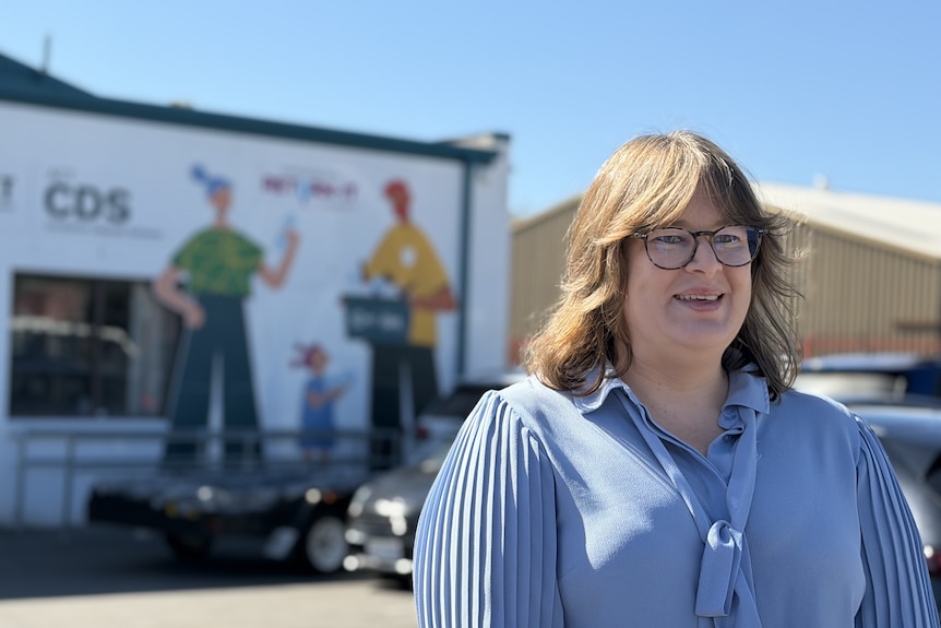 Minister Suzanne Orr wearing a blue top outside a container deposit depot.