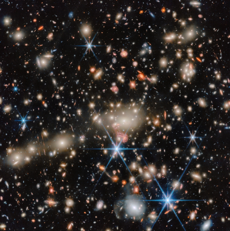 A myriad of tiny distant galaxies, with a group of very many small foreground galaxies.