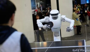The Sharpa North robot holds a paddle and plays table tennis against a person at a booth during CES 2026
