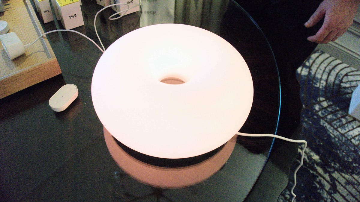 Ikea's glowing smart lamp and various devices on a table.