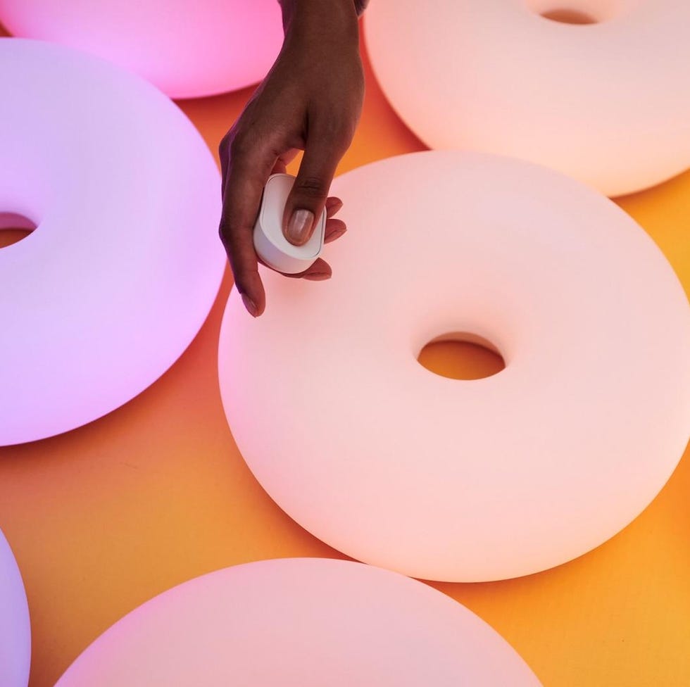 Ikea x Sabine Marcelis - VARMBLIXT lamp hand adjusting a light control on circular glowing objects