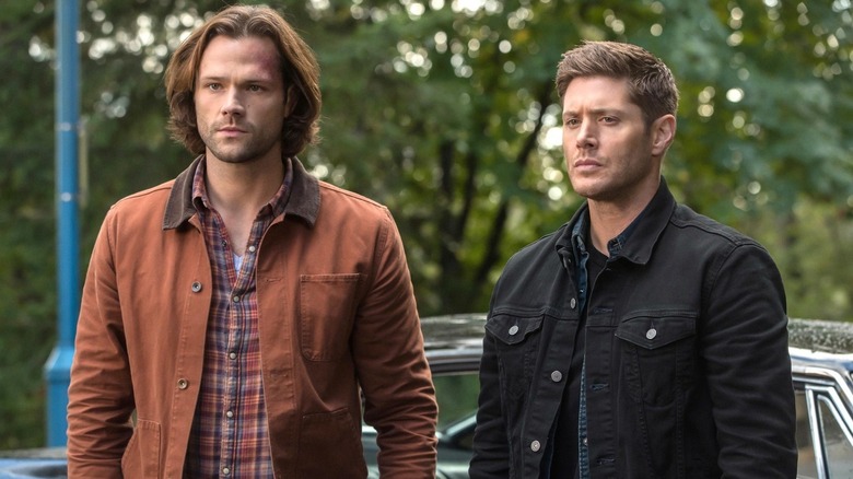 Sam and Dean Winchester standing in front of the Impala on Supernatural (2005-2020)