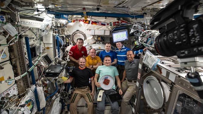 DEC. 12, 2025: The seven-member Expedition 74 crew gathers for a portrait inside the International Space Station's Kibo laboratory module. In the front row, from left, are Roscosmos cosmonauts Sergei Mikaev and Sergey Kud-Sverchkov, along with NASA astronaut Chris Williams. In the back row are JAXA (Japan Aerospace Exploration Agency) astronaut Kimiya Yui, NASA astronaut Mike Fincke, Roscosmos cosmonaut Oleg Platonov, and NASA astronaut Zena Cardman. Kud-Sverchkov (center) was celebrating 200 cumulative days in space with a slice of cake.