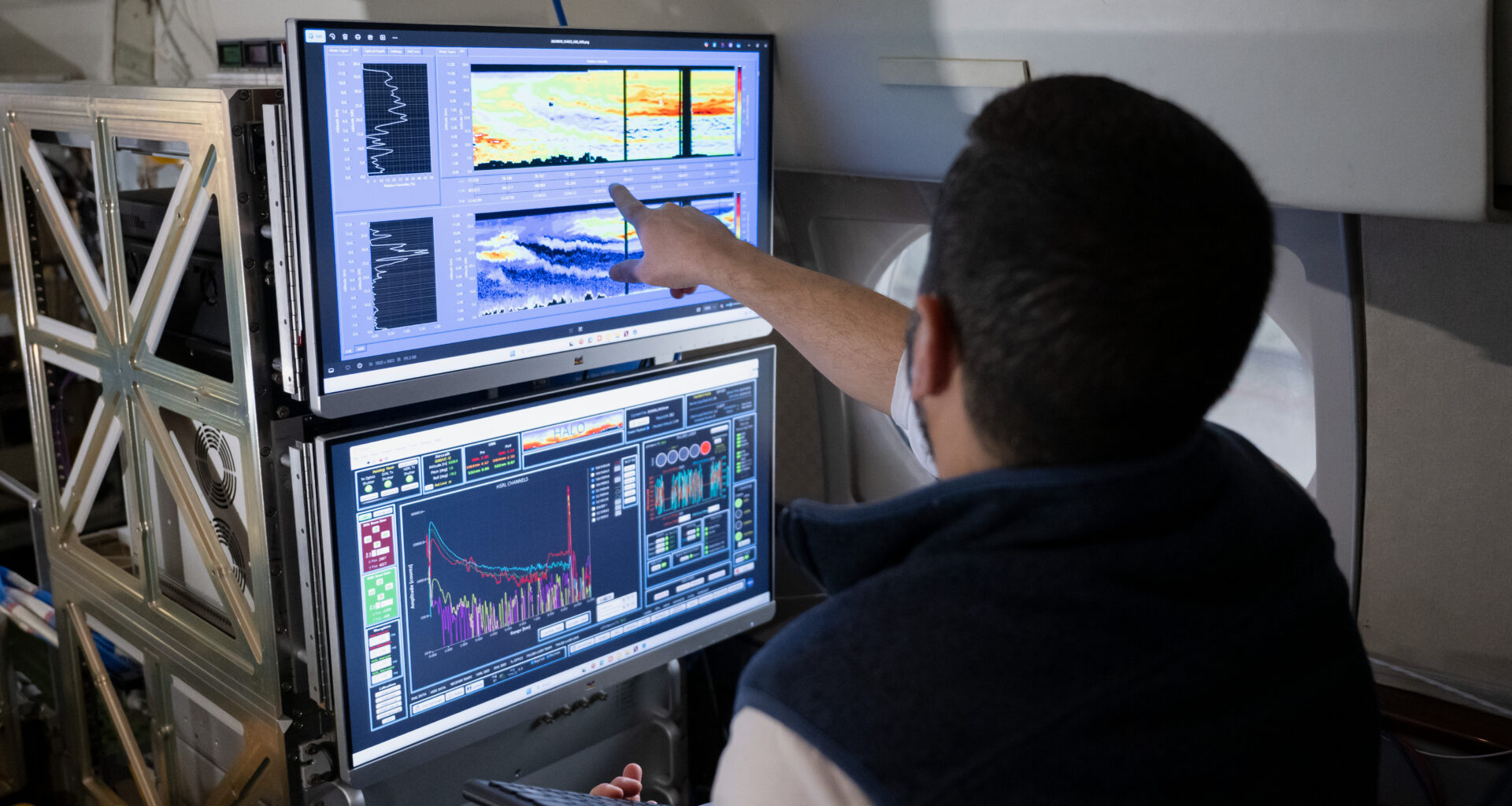 Two computer monitors are shown from the perspective of looking over a researcher's shoulder. The screens show colorful graphs representing smoke and aerosol measurements from previous missions with the HALO lidar instrument.