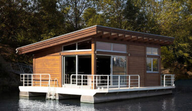 mono-pitch roof shields wooden cabin floating along river in serbia