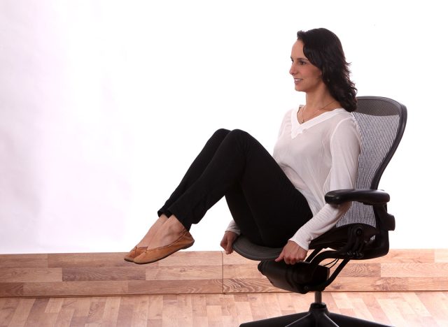 female manager stretching up on her chairs office .