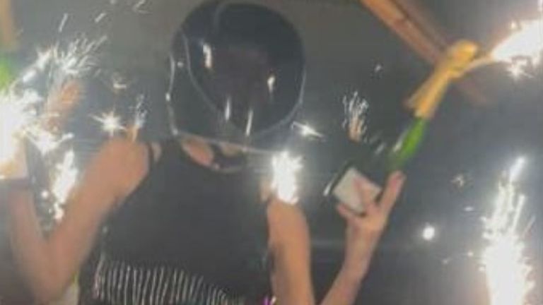 Photo shows woman on shoulders with sparklers in bottle before fire