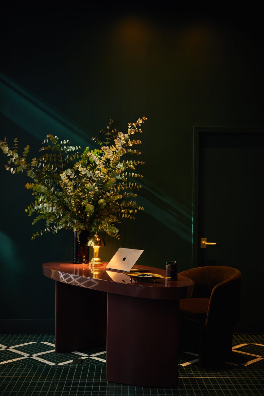 Lobby with a dark green palette and mosaic tiles, plus a lacquered burgundy desk