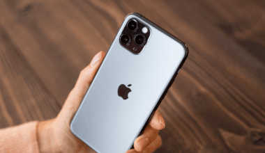 Person holding an iPhone with the Apple logo visible at the back.