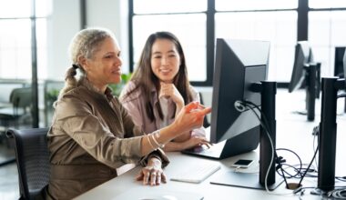 Two people in an office setting who are discussing something on a computer screen.
