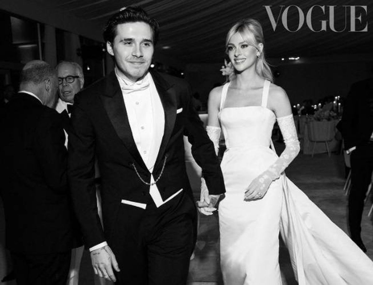 A black and white photograph of a couple dressed in formal attire, walking hand in hand, with the word "Vogue" prominently displayed at the top of the image.