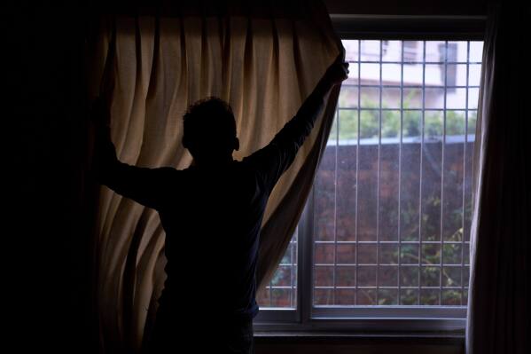 A Tibetan living in exile pulls the curtain before he gives an interview in Kathmandu, Nepal, April 14, 2025. (AP Photo/Niranjan Shrestha)