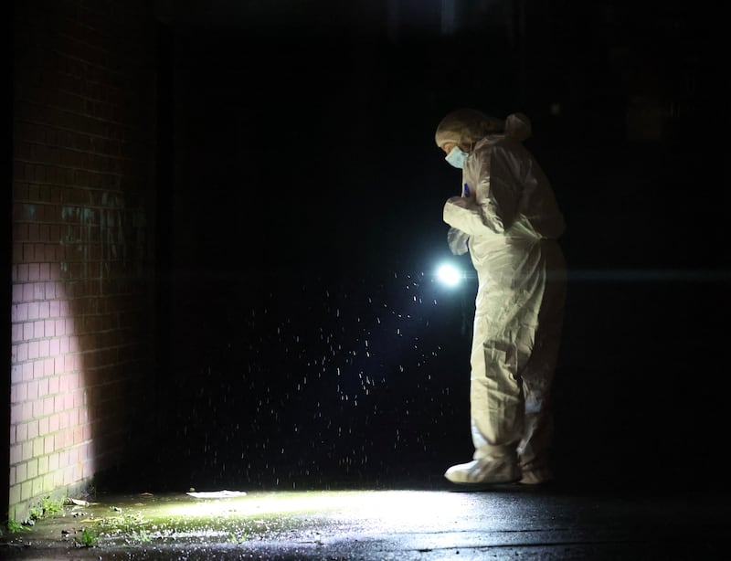 A forensic office searches an alley way.in the Ardoyne area where a man believed to have shot a number of times. PICTURE: MAL MCCANN