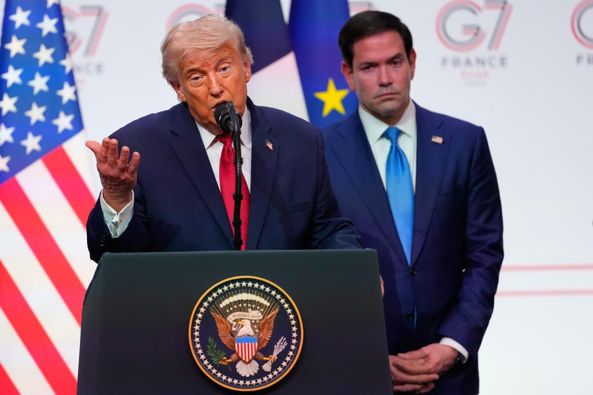 Donald Trump speaks at a podium with Marco Rubio behind him. 